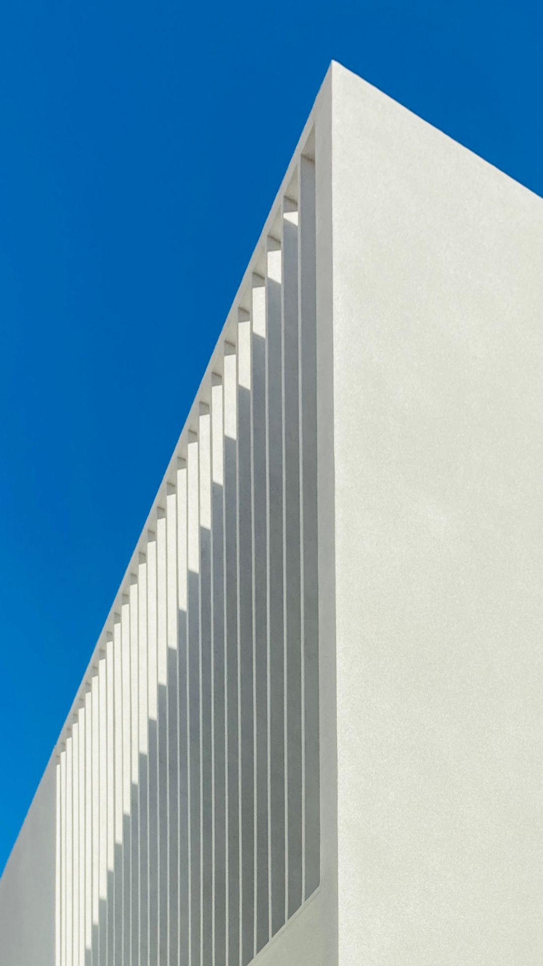 Detall geomètric d'una façana blanca sota el cel blau