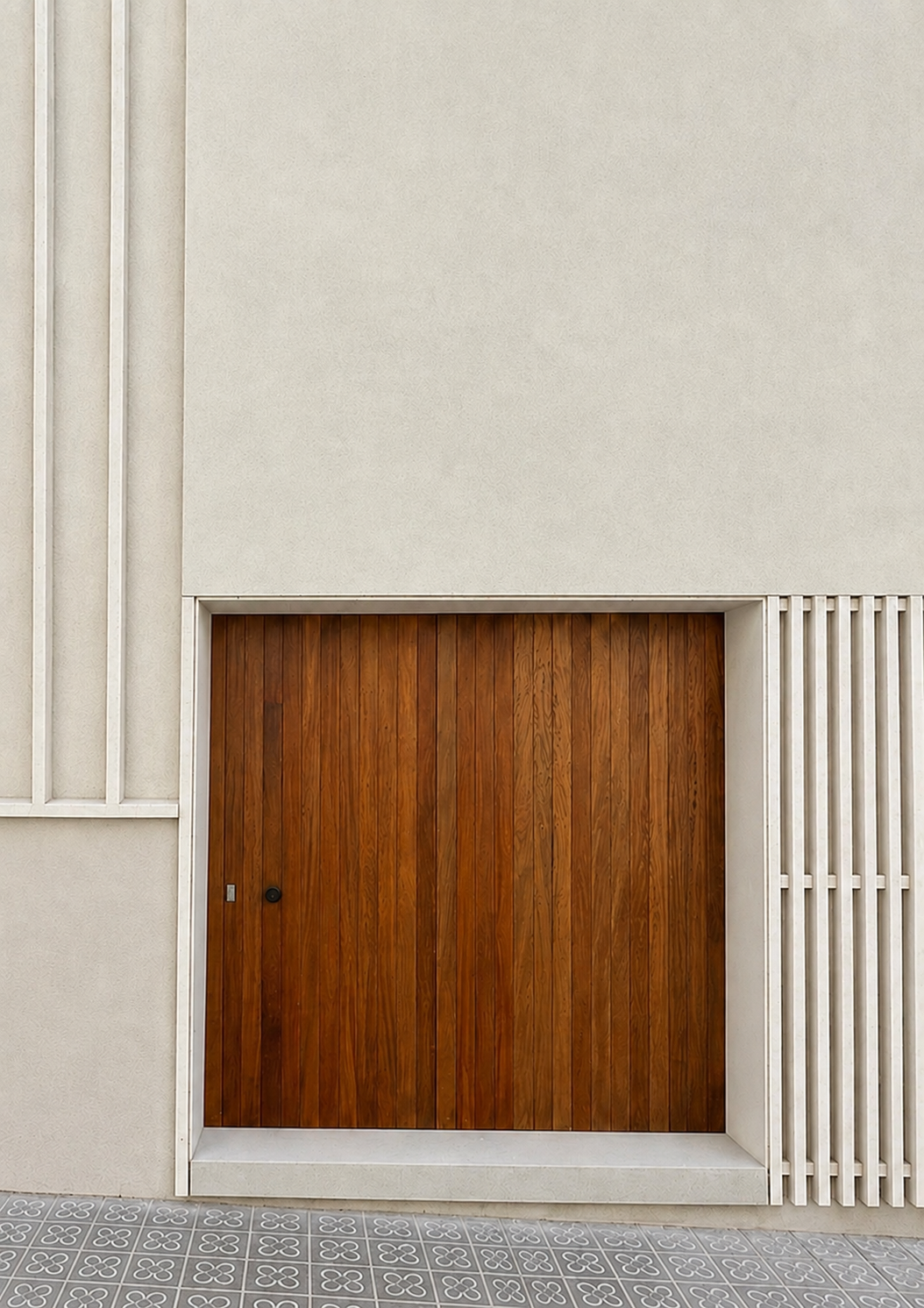 Porta de fusta emmarcada en una façana blanca amb brise-soleil
