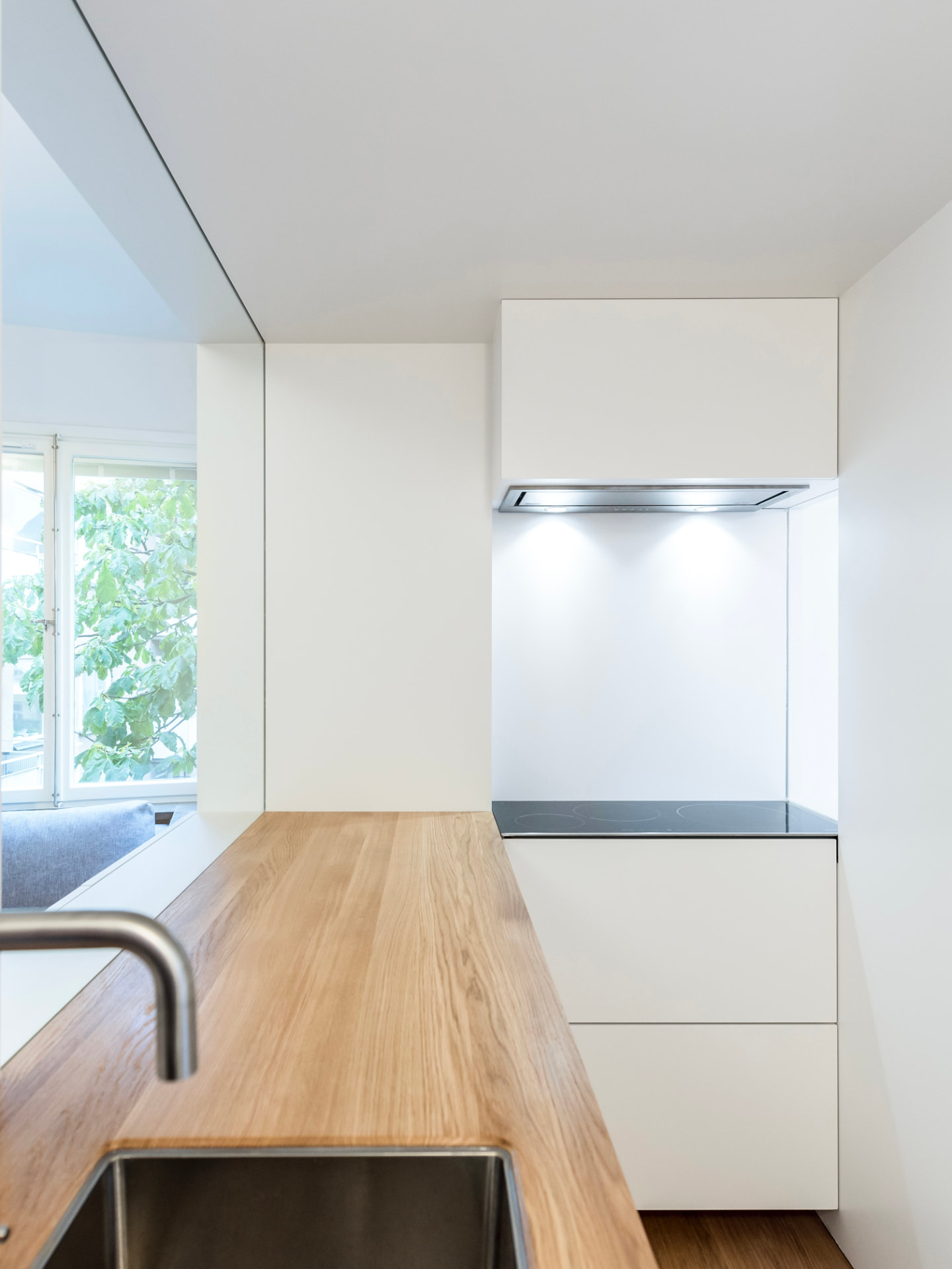 Cuina blanca minimalista amb taulell de fusta i llum natural